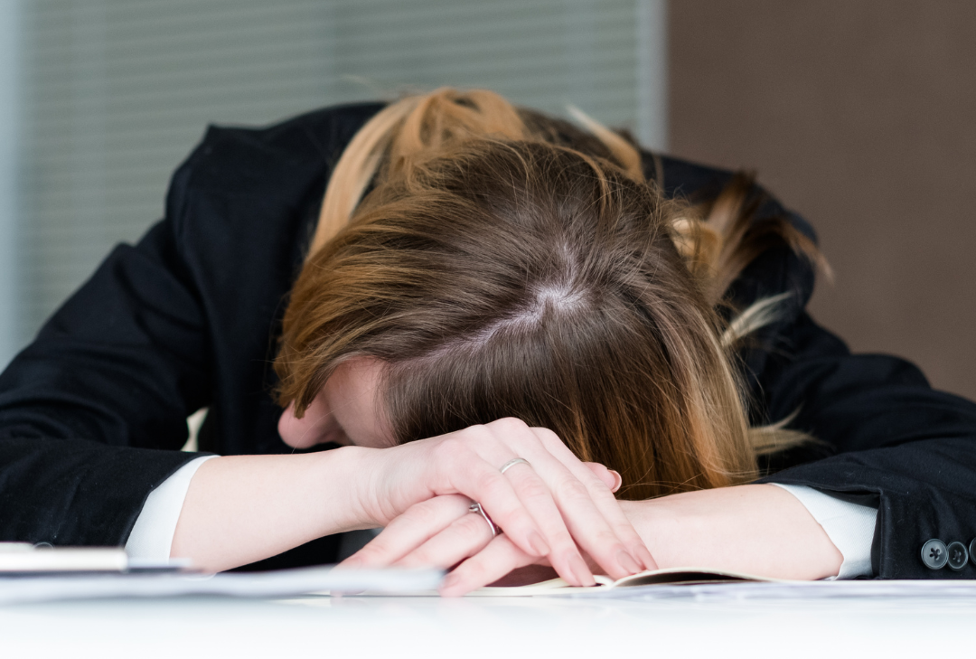 Woman sleeping at desk - is sleep deprivation a Health & Safety Risk?